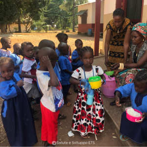 Operatori e bambini durante un momento di distribuzione e assistenza del Fondo AMOC